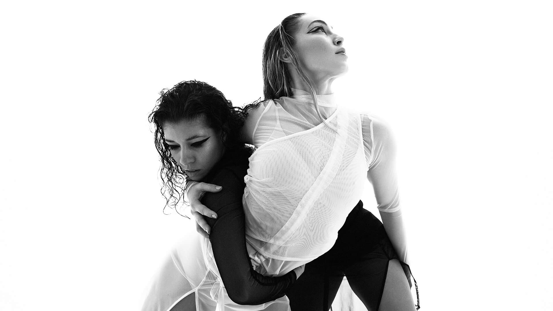Black and white photo of two intertwined female dancers, one in black, on the left, and the other in white, on the right.