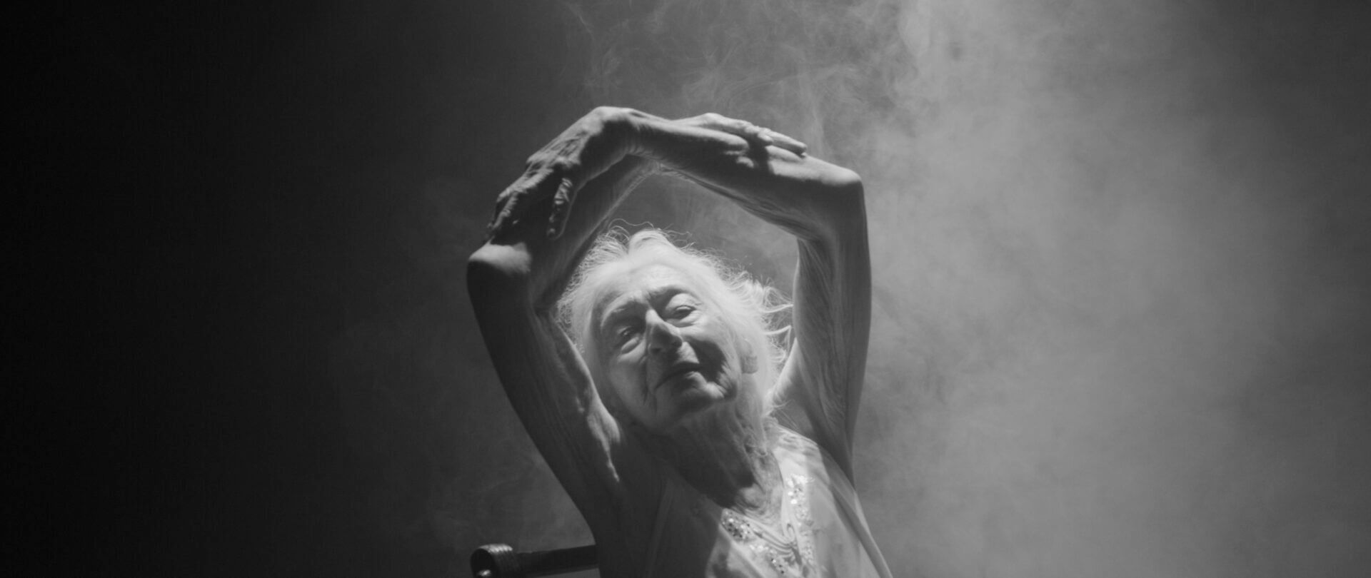 An image of an Eileen Kramer dancing with her hands above her head.